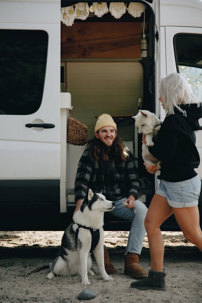 Couple enjoying a day outdoors with their dogs by a camper van, highlighting a love for travel and pets.